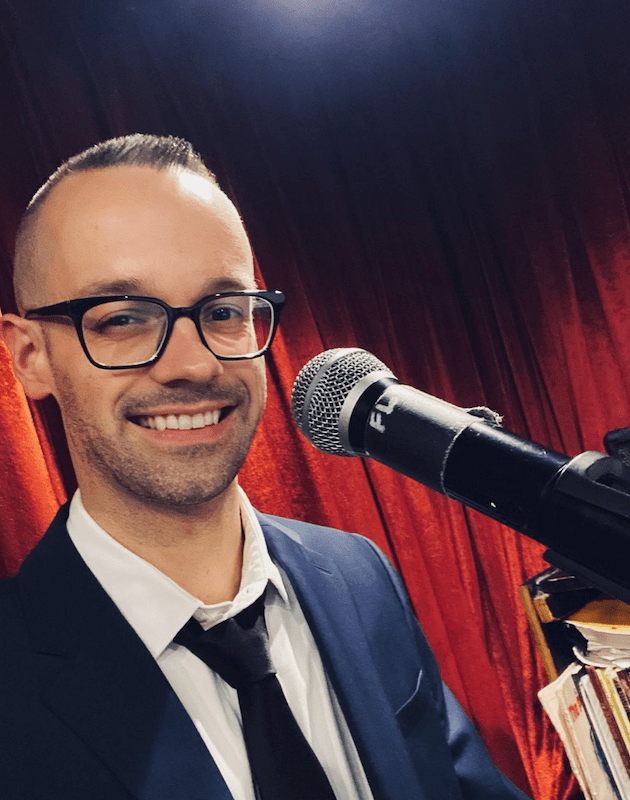 Jazz piano NYC, Matt Dorland pianist NYC smiling at the mic and piano at Don't Tell Mama